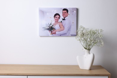 Photo of Canvas with printed photo of happy newlyweds on white wall indoors