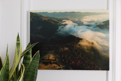 Canvas with printed photo of mountains on white wall indoors