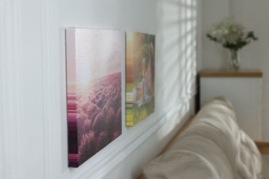 Canvas with different printed photos on white wall indoors