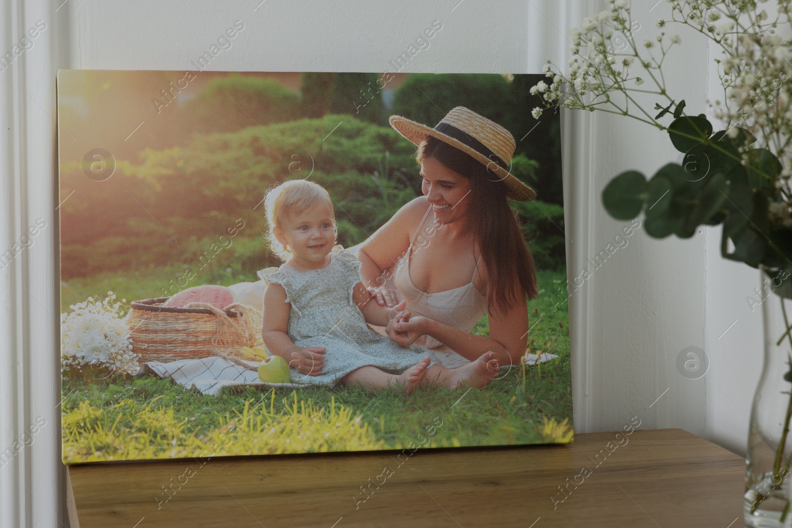 Photo of Canvas with printed photo of happy mother and her little daughter on wooden table indoors