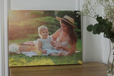 Canvas with printed photo of happy mother and her little daughter on wooden table indoors