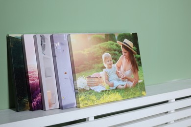 Photo of Canvas with different printed photos on shelf near green wall