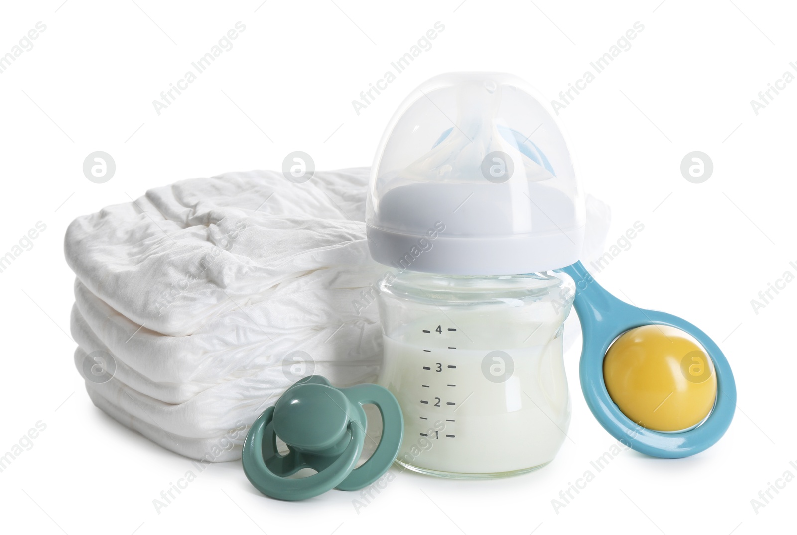 Photo of Feeding bottle with milk, diapers, baby rattle and pacifier isolated on white