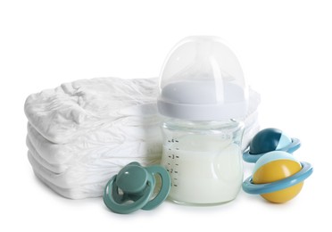 Photo of Feeding bottle with milk, diapers, baby rattle and pacifier isolated on white