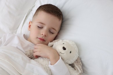 Bedtime. Cute boy sleeping with toy sheep in bed