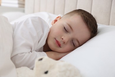 Bedtime. Cute boy sleeping with toy sheep in bed