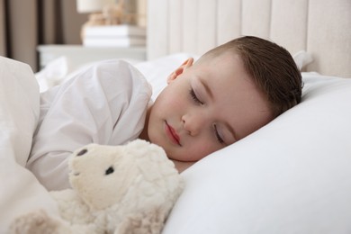 Bedtime. Cute boy sleeping with toy sheep in bed