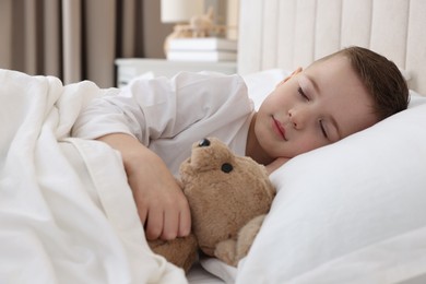 Photo of Bedtime. Cute boy sleeping with his teddy bear in bed