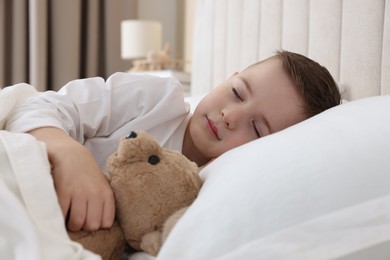 Photo of Bedtime. Cute boy sleeping with his teddy bear in bed