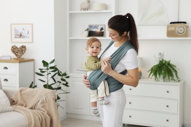 Photo of Mother holding her child in sling (baby carrier) at home