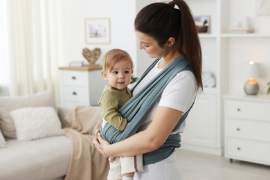 Photo of Mother holding her child in sling (baby carrier) at home