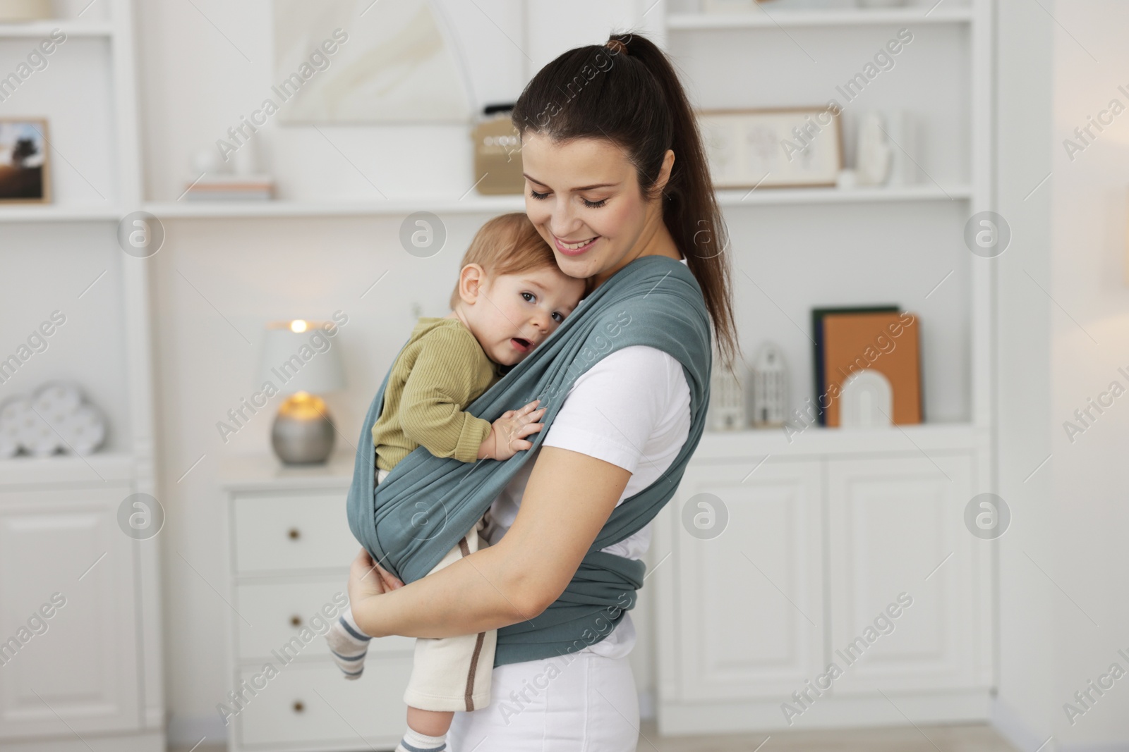 Photo of Mother holding her child in sling (baby carrier) at home