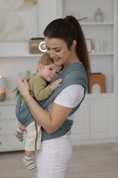 Mother holding her child in sling (baby carrier) at home