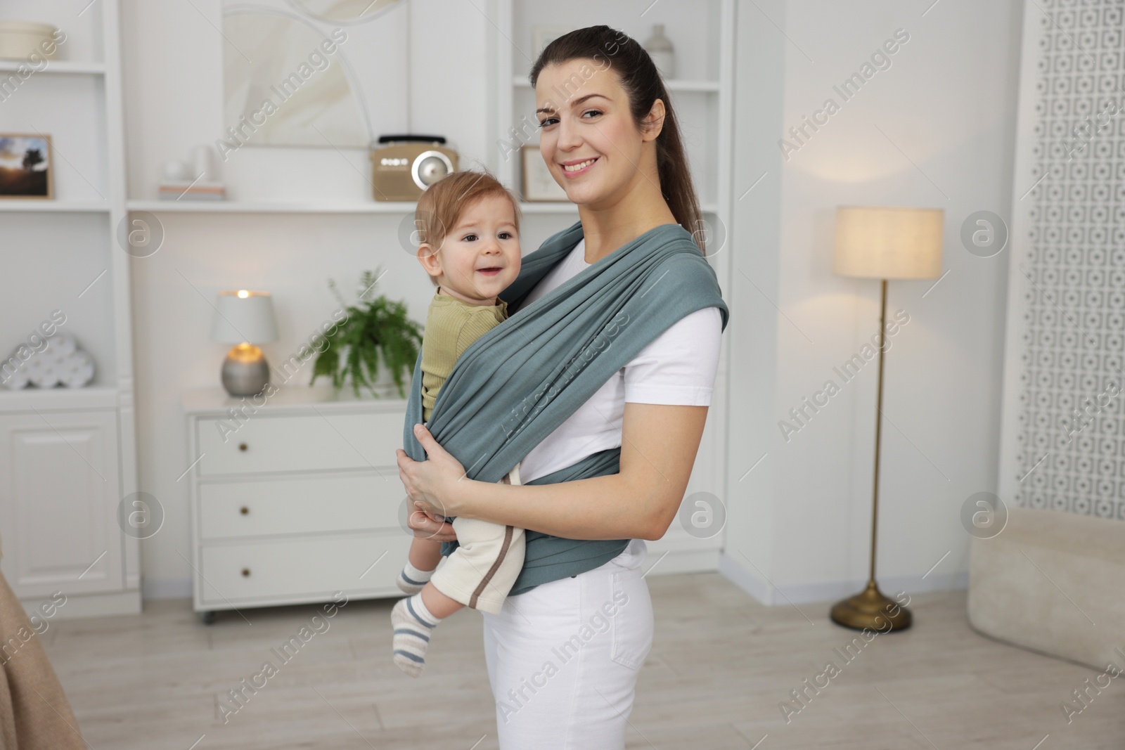 Photo of Mother holding her child in sling (baby carrier) at home