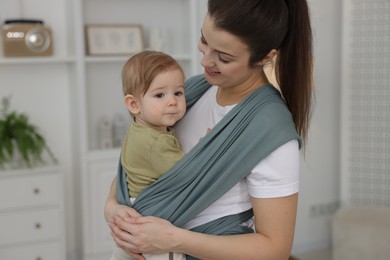 Photo of Mother holding her child in sling (baby carrier) at home