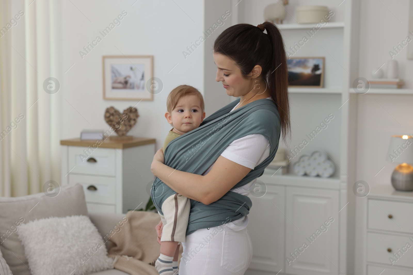 Photo of Mother holding her child in sling (baby carrier) at home