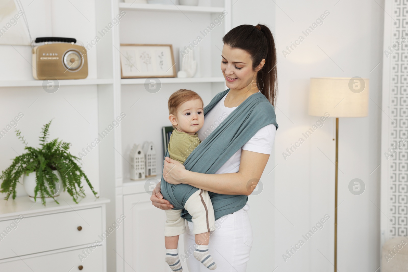 Photo of Mother holding her child in sling (baby carrier) at home