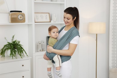 Mother holding her child in sling (baby carrier) at home