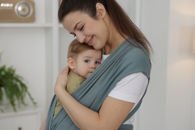 Mother holding her child in sling (baby carrier) at home