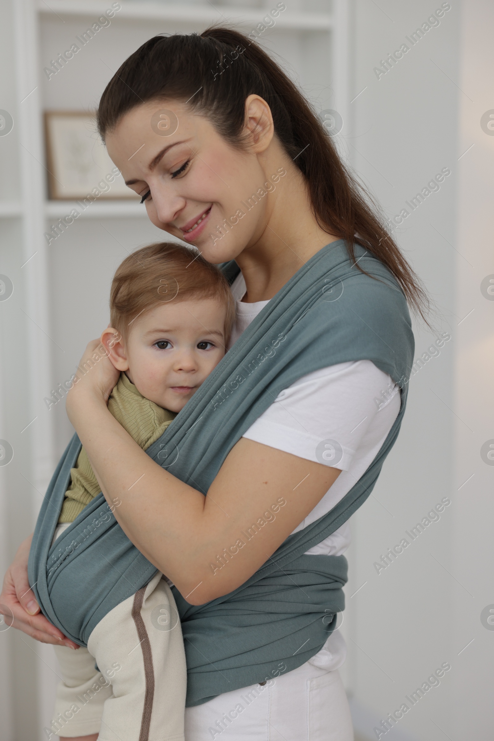 Photo of Mother holding her child in sling (baby carrier) at home