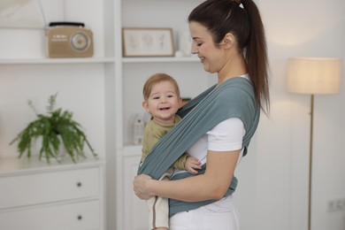 Mother holding her child in sling (baby carrier) at home