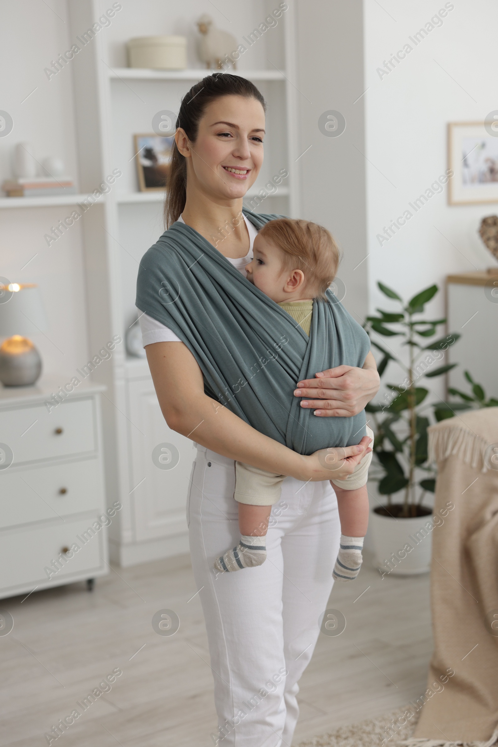 Photo of Mother holding her child in sling (baby carrier) at home