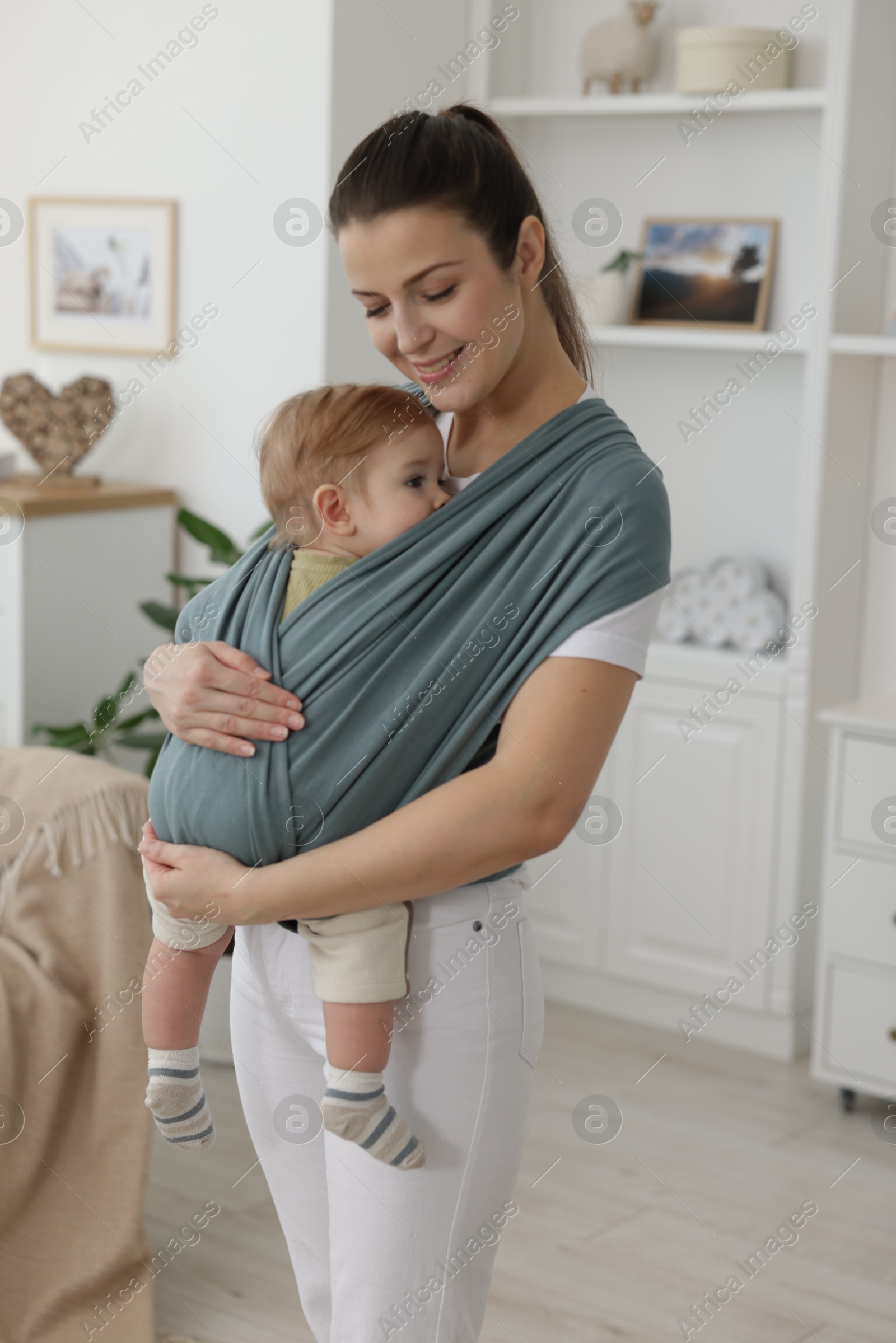 Photo of Mother holding her child in sling (baby carrier) at home