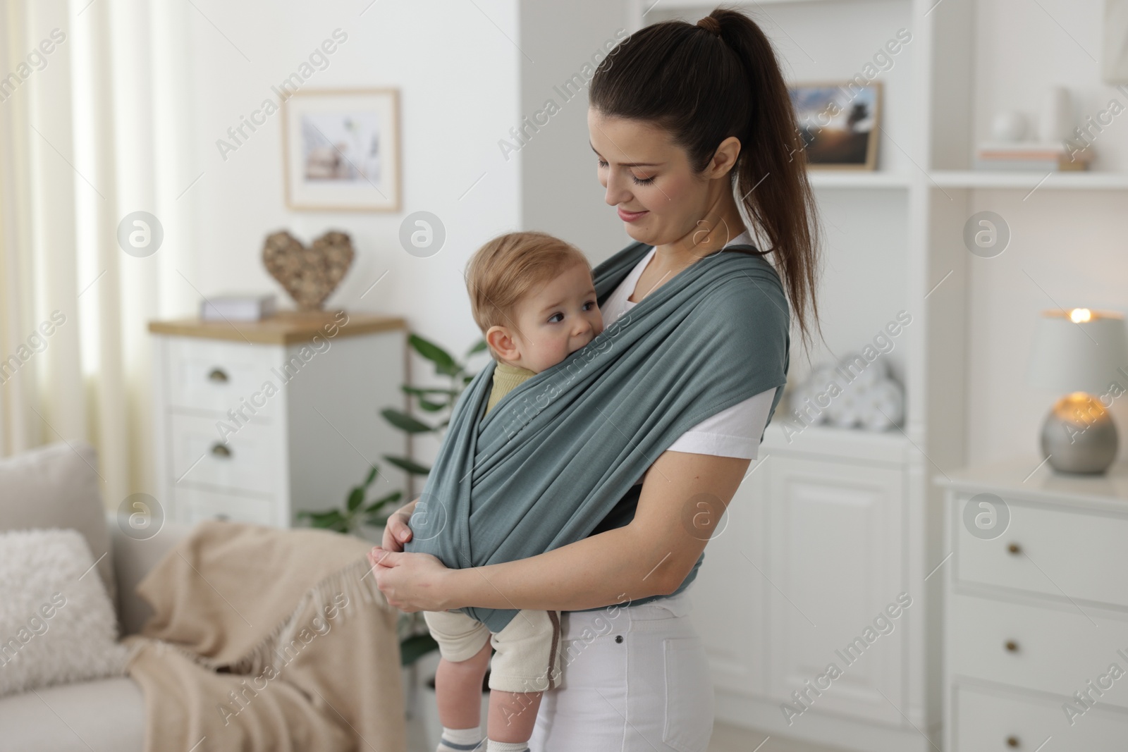 Photo of Mother holding her child in sling (baby carrier) at home