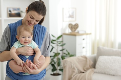 Photo of Mother holding her child in sling at home, space for text