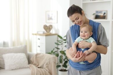 Photo of Mother holding her child in sling at home, space for text