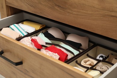 Organizers with folded clothes in drawer, closeup