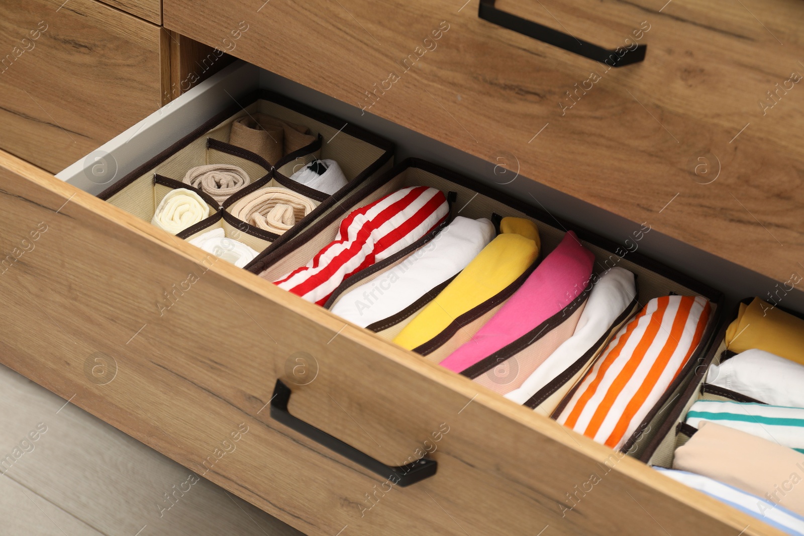 Photo of Organizers with folded clothes in drawer indoors, closeup