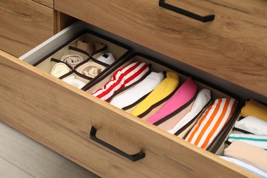 Organizers with folded clothes in drawer indoors, closeup