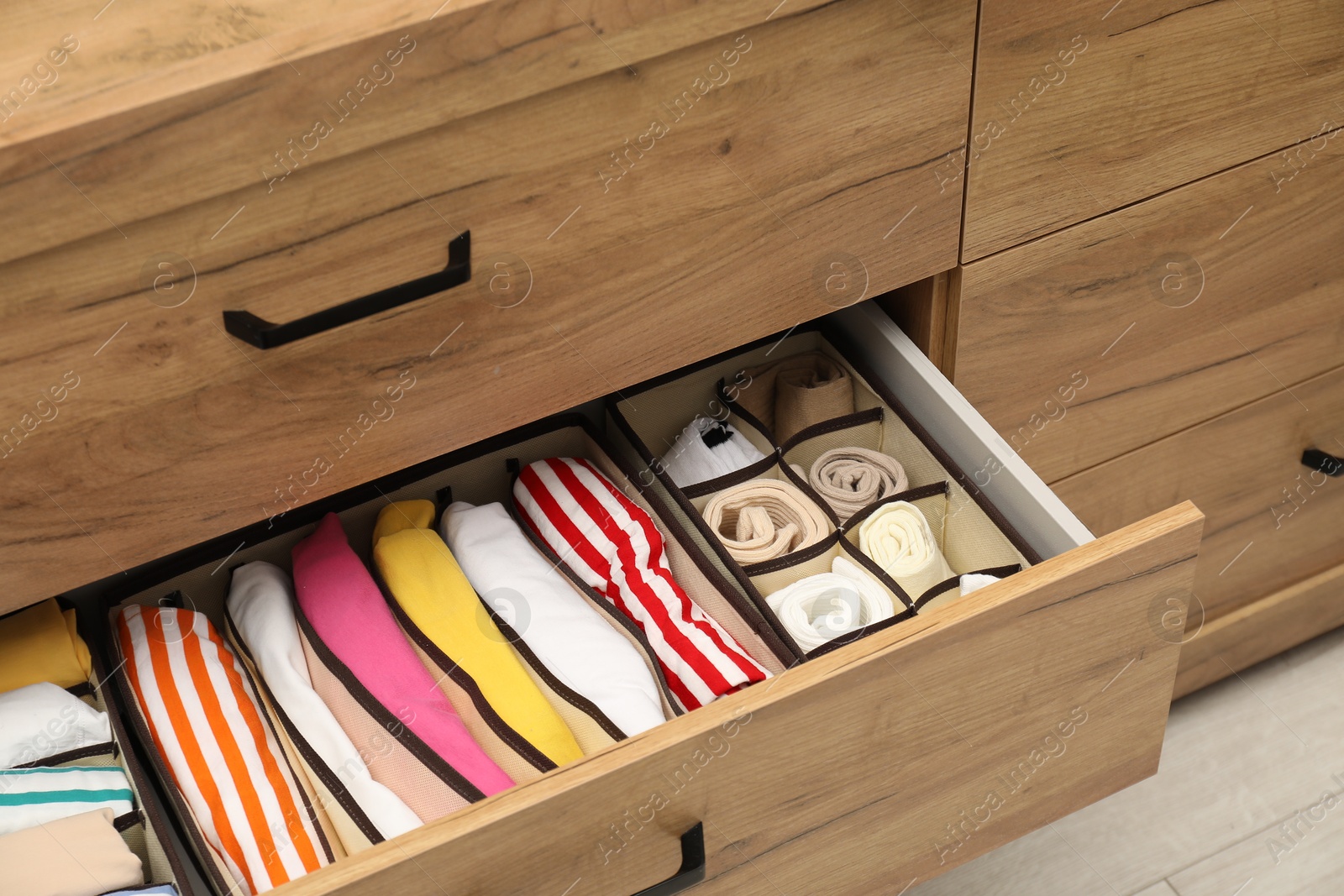 Photo of Organizers with folded clothes in drawer indoors, closeup