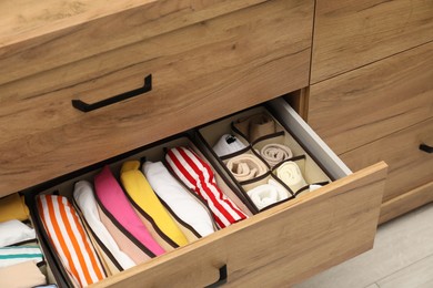 Photo of Organizers with folded clothes in drawer indoors, closeup