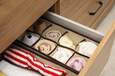 Organizers with folded clothes in drawer indoors, closeup