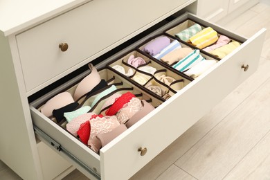 Photo of Organizers with folded clothes in drawer indoors, closeup