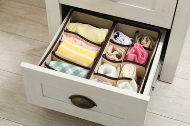 Photo of Organizers with folded clothes in drawer indoors, closeup