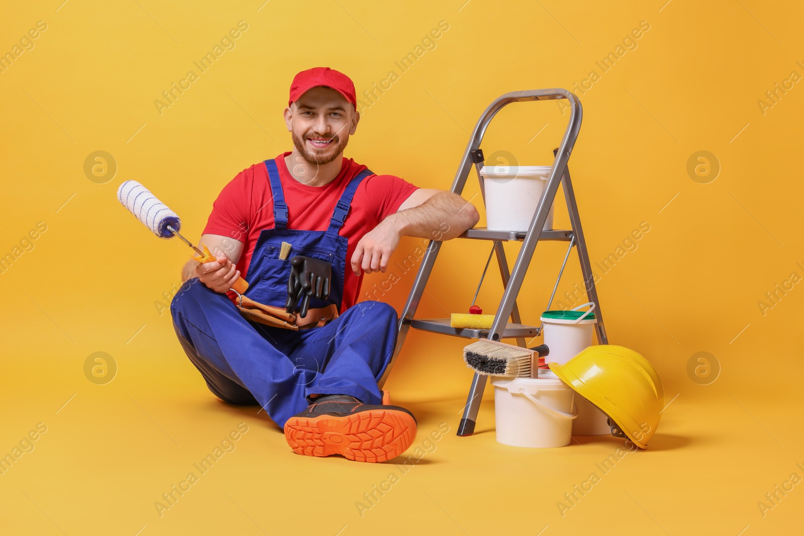 Photo of Professional painter with tools and supplies on orange background