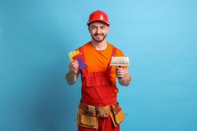 Photo of Professional painter with brush and color samples on light blue background