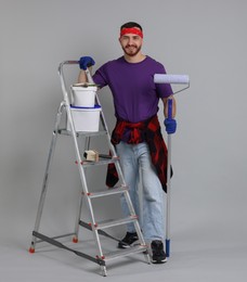 Man with tools and supplies on light grey background