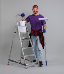 Man with tools and supplies on light grey background. Space for text