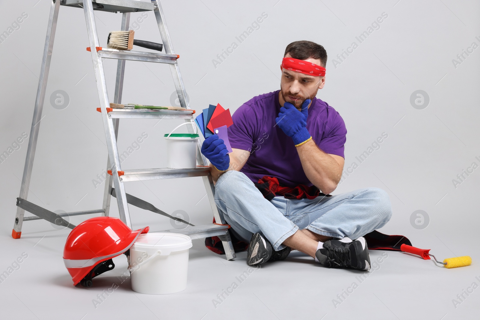 Photo of Pensive man with tools and supplies on light grey background