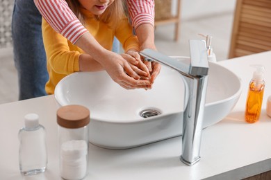 Mother and daughter washing their hands indoors, closeup