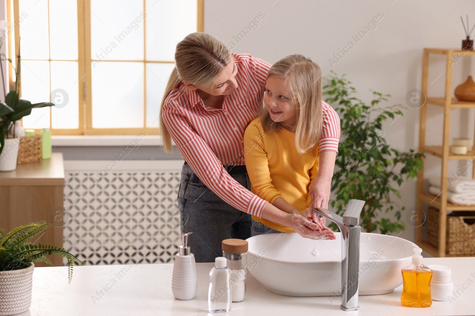 Photo of Happy mother and daughter washing their hands in bathroom