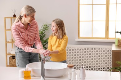 Photo of Happy mother and daughter washing their hands in bathroom. Space for text