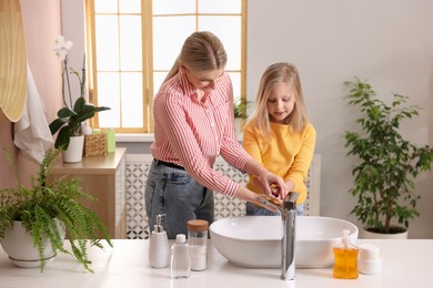 Mother and daughter washing their hands in bathroom