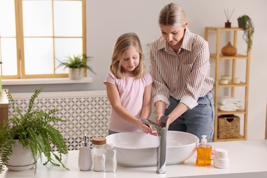 Photo of Mother and daughter washing their hands in bathroom