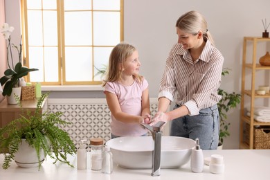 Photo of Happy mother and daughter washing their hands in bathroom