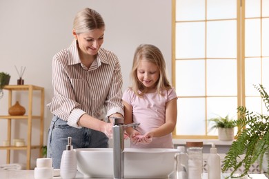 Photo of Happy mother and daughter washing their hands in bathroom